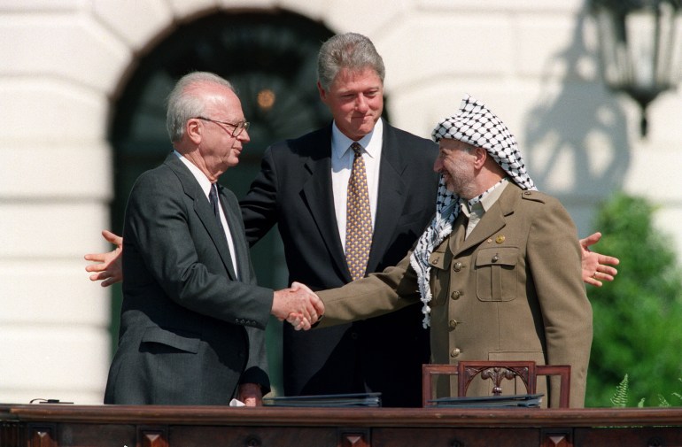 US President Bill Clinton (C) stands between PLO leader Yasser Arafat (R) and Israeli Prime Minister Yitzahk Rabin (L) as they shake hands for the first time, on September 13, 1993 at the White House in Washington DC, after signing the historic Israel-PLO Oslo Accords on Palestinian autonomy in the occupied territories. (Photo by J. DAVID AKE / AFP)