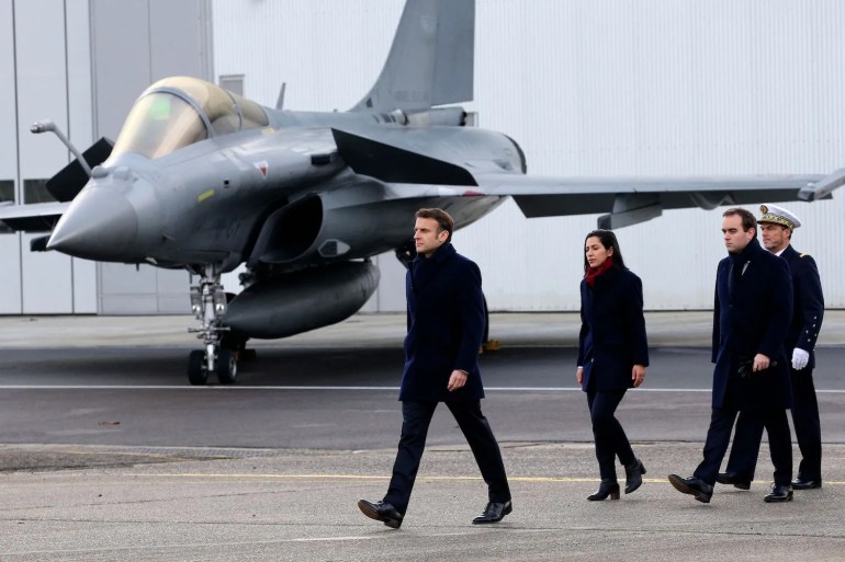 French President Emmanuel Macron, followed by French Armies Minister Sebastien Lecornu (2nd R), walks past a Dassault Rafale fighter aircraft during his New Year address to the French Army at the Mont-de-Marsan air base, southwestern France, on January 20, 2023. (Photo by Bob Edme / POOL / AFP)