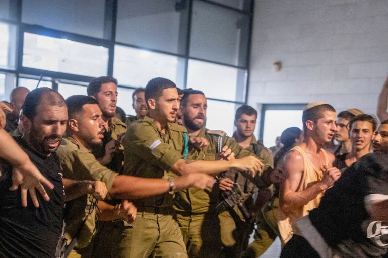 Israeli soldiers and police clash with right wing protesters, after they broke into the†Bayt Lid army base over the detention for questioning of military reservists who were suspected of abuse of a detainee following the October 7 attack in Israel, on July 29, 2024 in Kfar Yona. - The Israeli military said on July 29 nine soldiers were being held in a case of suspected abuse of a Palestinian detainee at a facility holding Palestinians arrested from Gaza during the war. (Photo by Oren Ziv / AFP)