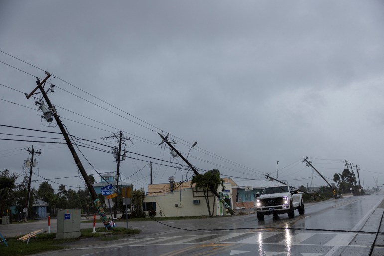 A motorist drives past broken utility poles downed by strong wind gusts as Hurricane Milton approaches Fort Myers, Florida, U.S. October 9, 2024. REUTERS/Ricardo Arduengo