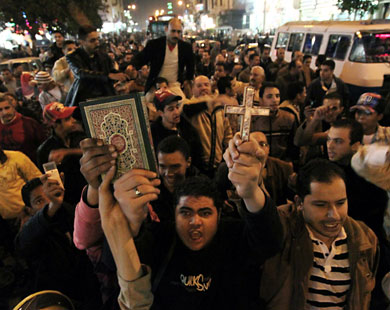 epa02512589 Egyptian Muslims and Christians raise the Quran and Cross in Shobra district, Cairo, Egypt, to protest against the terrorist attack on a Coptic Christian church in the northern Egyptian city of Alexandria,