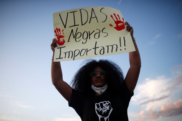 امرأة ترفع لافتة كتب عليها: Vidas Negras Importam.